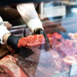 Closeup,On,Butcher’s,Hands,In,Gloves,Working,In,Butchery.
